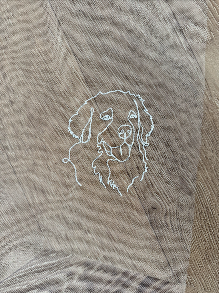 Portrait minimaliste d'un chien brodé sur un voile de mariée.