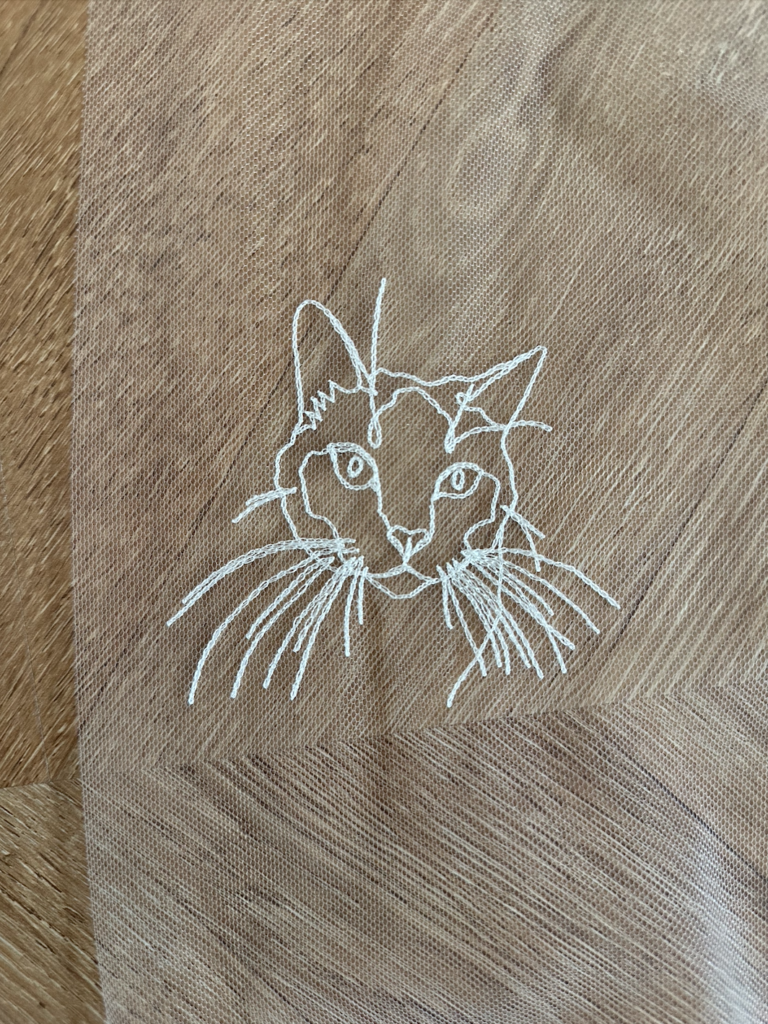 Portrait détaillé d'un chat brodé à la main sur un voile de mariée.