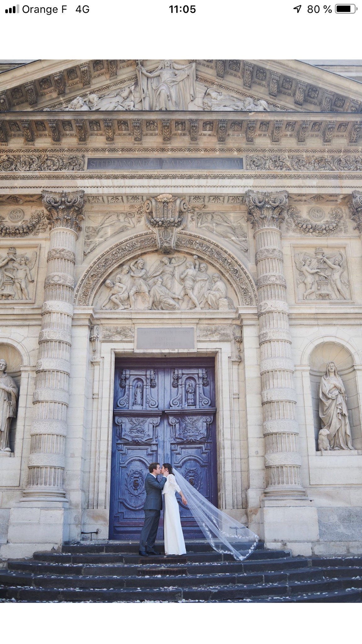 Mariée portant un voile cathédrale long devant une église
