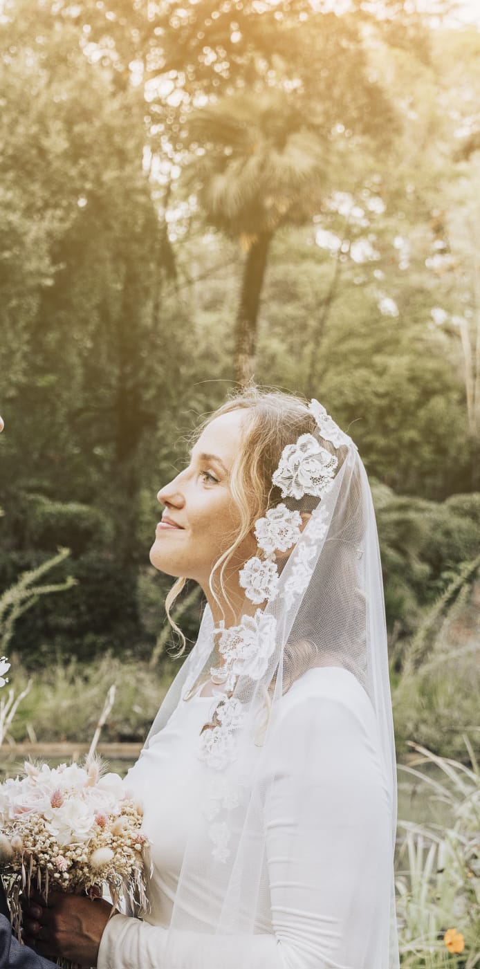 Mariée portant un voile en dentelle florale lors d'un mariage en extérieur