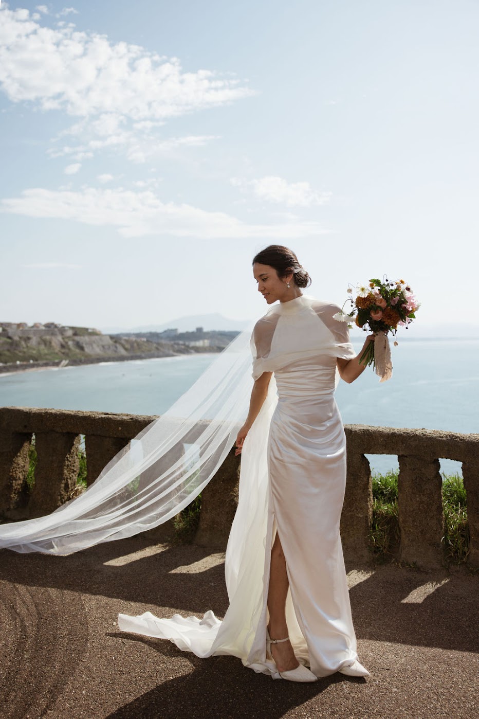 Mariée portant un voile long en tulle au bord de la mer