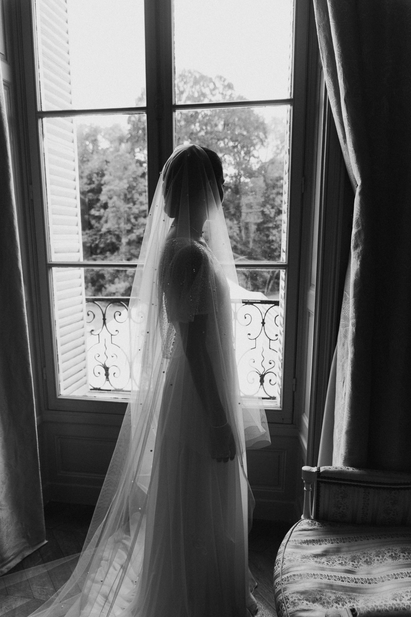 Silhouette de mariée portant un voile perlé devant une fenêtre